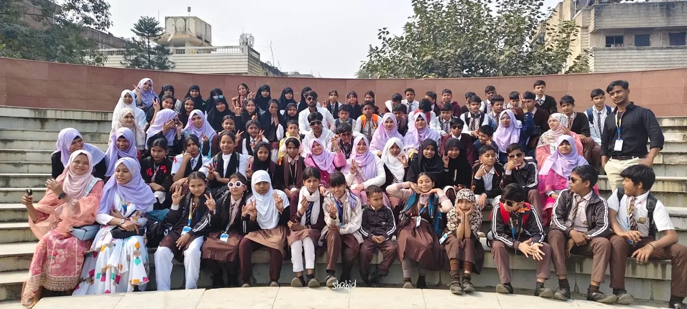 A large group of students and teachers pose together on outdoor stone steps.